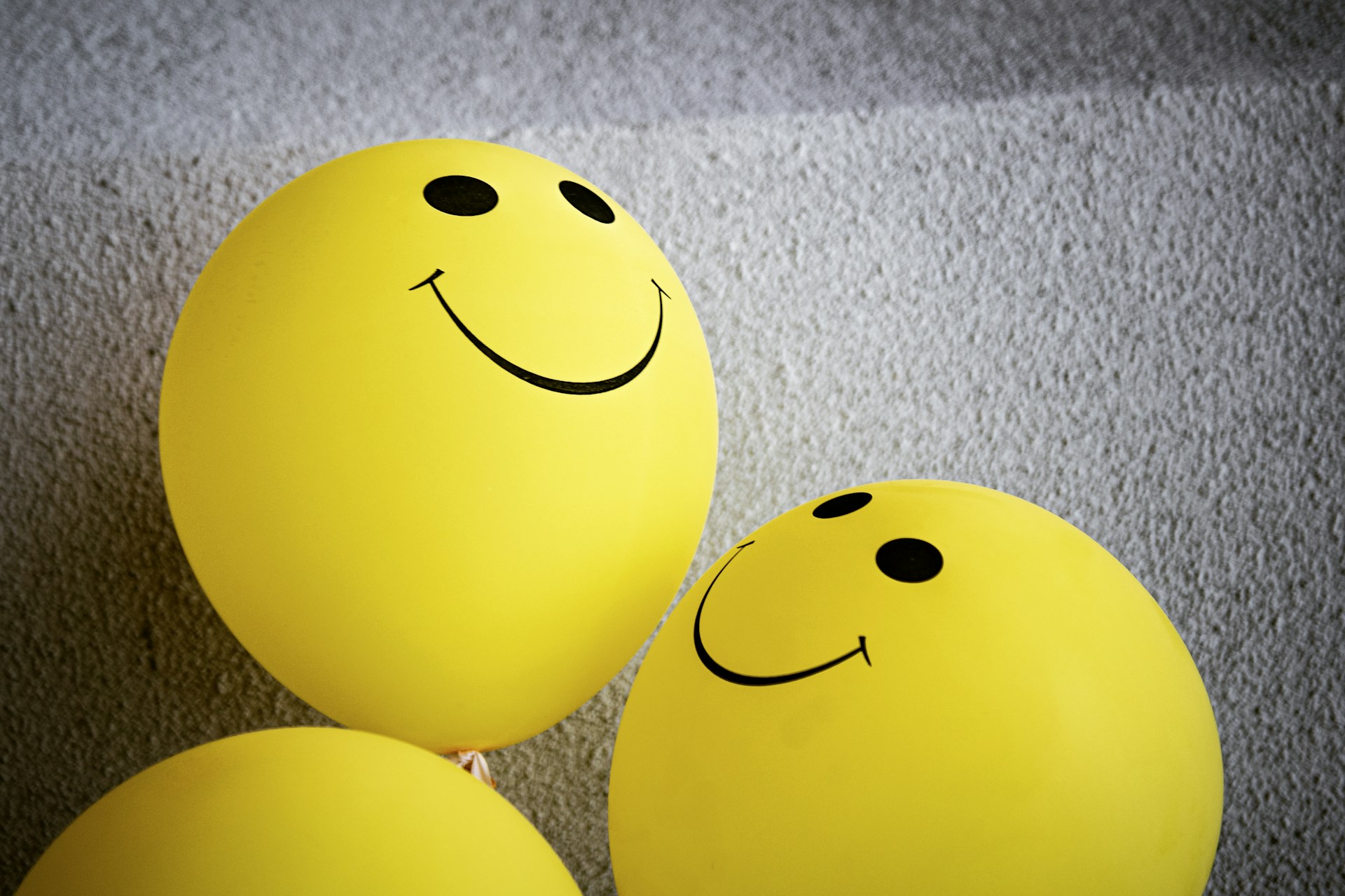 yellow smiley emoji balloons on grey textile