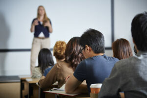 Female academic giving lecture to room of students